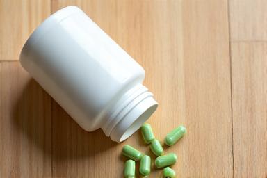 Probiotic capsules spilling from a bottle onto a wooden surface